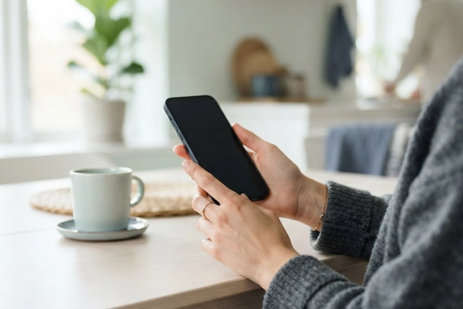 Hands holding a phone at a kitchen table