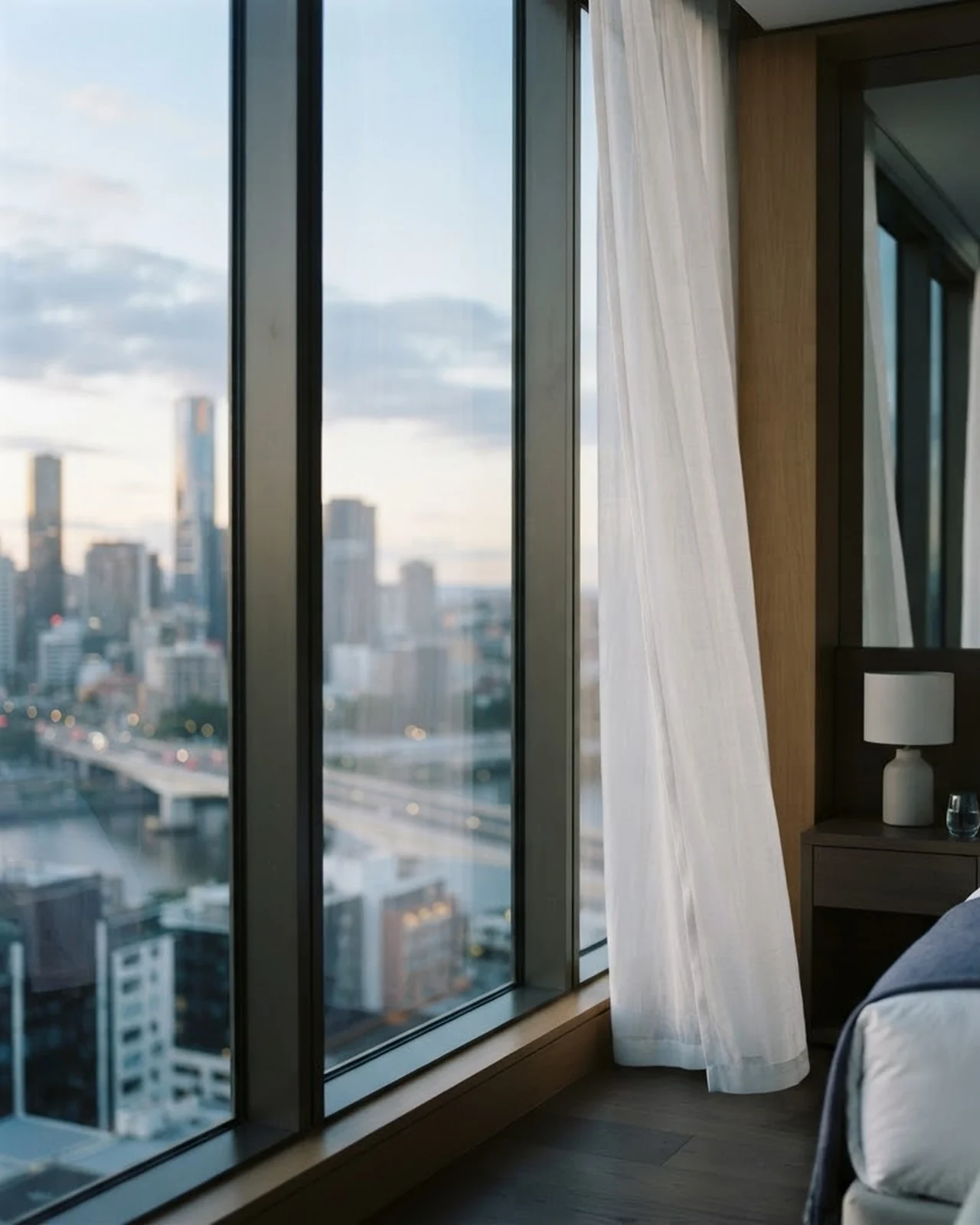 A hotel window looking out over a city at dawn