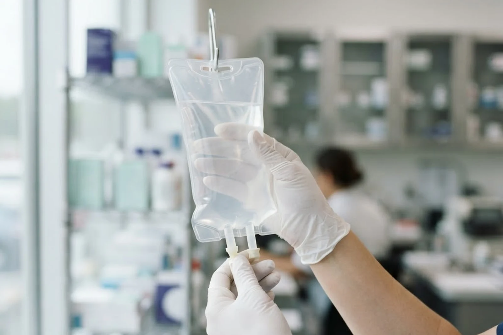 Gloved hands inspecting an IV bag against the light